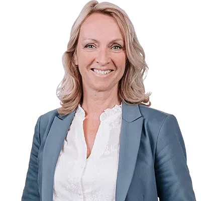 Vriendelijke professionele vrouw met blond haar in een blauw colbert en witte blouse, glimlachend en recht in de camera kijkend, tegen een neutrale achtergrond.